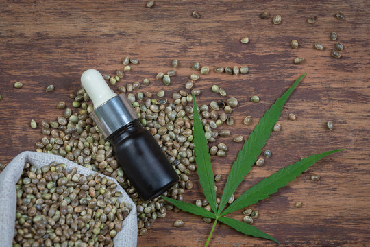 CDB Concept. Thai cannabis. A hemp oil bottle that is placed combined with seeds and peaks on a brown wooden floor.