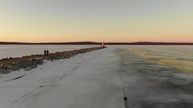 Petoskey Lighthouse Sunset Orange Sky Winter North Frozen Lake Michigan Cold Snow Ice Amazing Beautiful Aerial Flying Pier Ocean Ice Age Global Warming Fresh Water Lake in 4K final logo shot