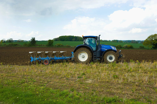 A tractor harrowing, ploughing in the stubble in a field. ,Farming