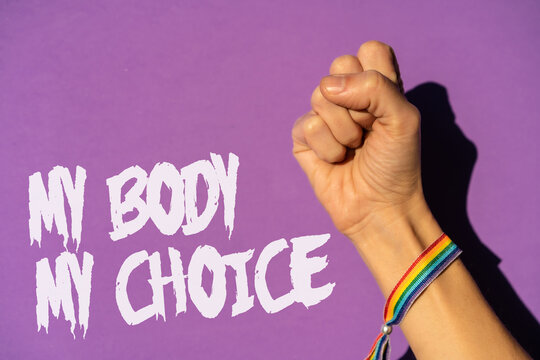 A woman with her fist raised and a text in favor of the legalization of abortion. Protest not to make abortion illegal in the united states, pro-choice, pro-life, on a purple background