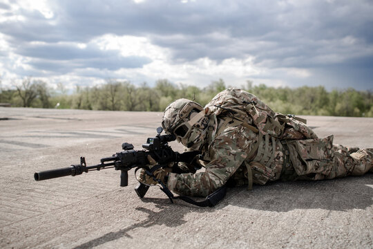 Military sniper aiming with sniper rifle lying on the roof