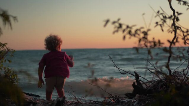 Silhouette Shot of Little Boy Throwing Rocks into the Water at the Beach During Sunset