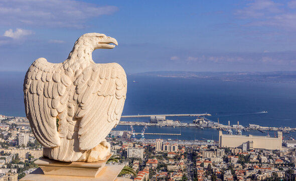 The statue of eagle on the fence at Bahai garden with the view on the Israeli city of Haifa, port, and Mediterranean sea.