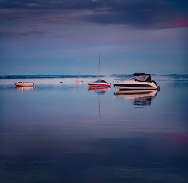 Dark summer seascape of Baltic sea with motorboats and yachts with a huge fog on background. Clody sky reflected in the calm waters of Baltic sea. Amazing sunrise on Rewa public beach, Poland.