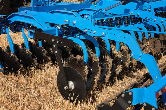 Close-up of a large modern plow blue color or disc harrow for cultivating the land. New model of agricultural equipment.