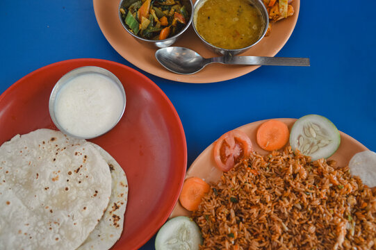 Overhead view of dal bhat tarkari set or rice and lentil soup, chicken biryani, juju dhau or yogurt and roti, authentic local Nepalese daily staple food