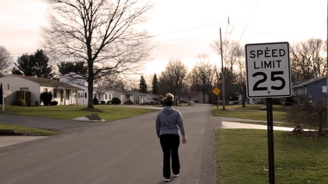 Woman walks past twenty five miles an hour sign