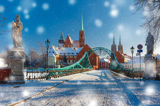 Tumski Bridge and Island with Cathedral of St. John and church of the Holy Cross and St. Bartholomew in the snowy overcast winter day in Wroclaw, Poland