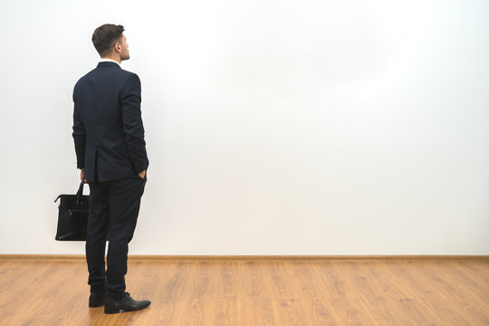 The man with a case standing on the white wall background