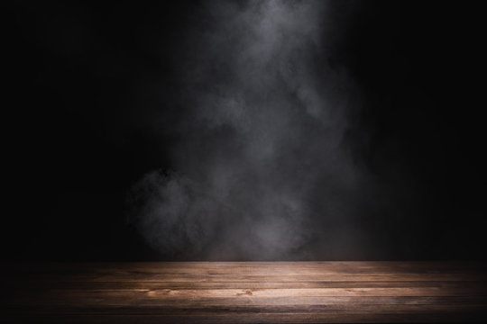 empty wooden table with smoke float up on dark background