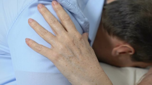 Son hugging mother in hospital room after heart attack, serious illness, therapy