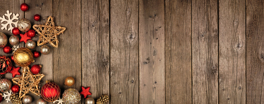 Red and gold Christmas ornament corner border banner. Above view on a rustic wood background.