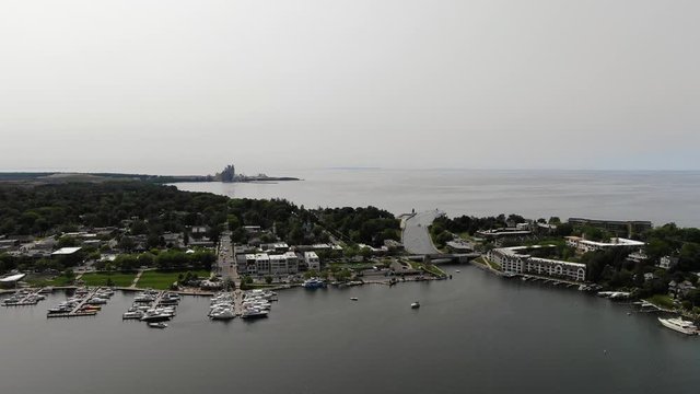 Round Lake in Charlevoix connects to Lake Michigan with boats and sail boats tied to dock at marina in Northern Michigan on a warm summer day drone flight logo placed here