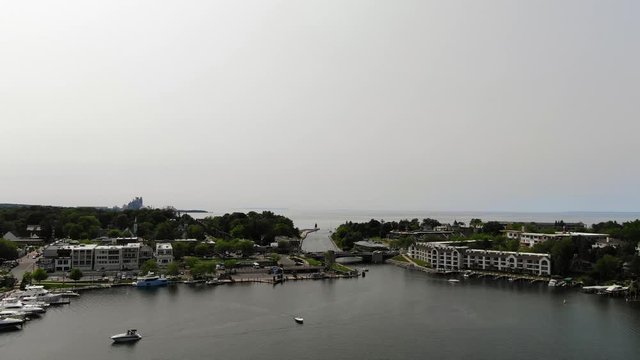 Round Lake in Charlevoix connects to Lake Michigan with boats and sail boats tied to dock at marina in Northern Michigan on a warm summer day drone flight logo here shot ending