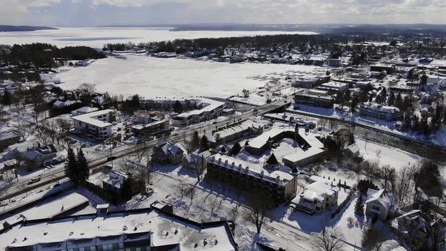 Winter in Charlevoix Michigan with hotel resorts covered in snow and Ice on Lake Michigan drone aerial shot looking up to clouds great for logo placement.