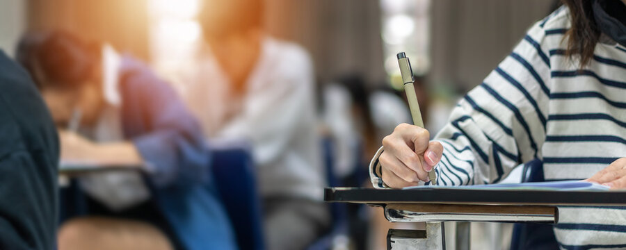 Exam at school with student's taking educational admission test in class, thinking hard, writing answer in university classroom, education and world literacy day concept