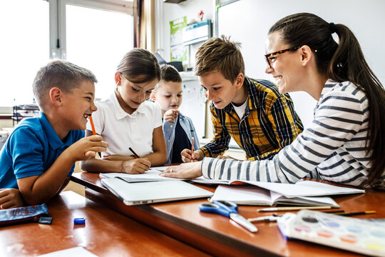 A kind female teacher spends time with her elementary school students, making learning enjoyable and fun while sparking curiosity and fostering a love for education. 