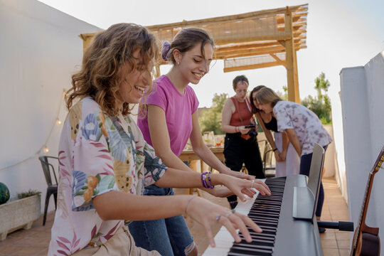 Teen girls playing electric organ at party 