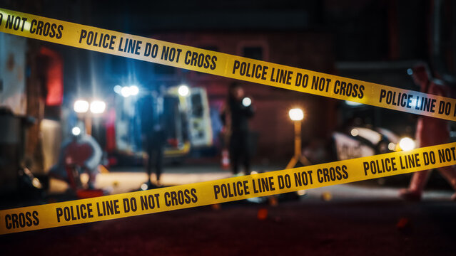 Crime Scene at Night: Crime Scene Investigation Team Working on a Murder. Female Police Officer Briefing Detective on the Victim's Body. Forensics and Paramedics Working. Cinematic Shot