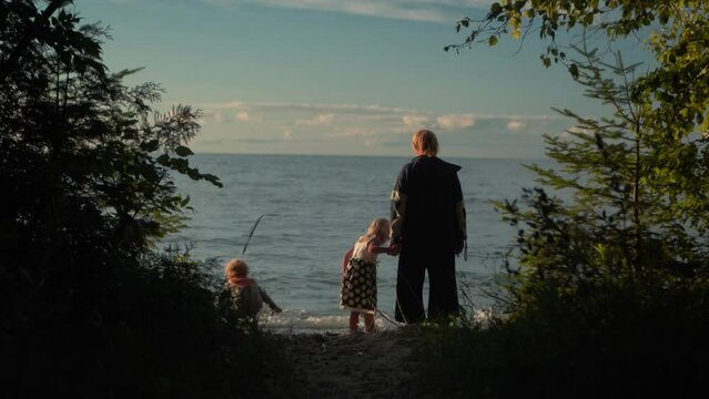 Silhouette Shot of Mother and Children Playing in the Water at the Beach During Sunset