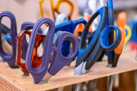 Closeup of scissors collection in a wooden rack in craftsmanship class in Waldorf school. Sewing lesson equipment. Handcraft supply for workshop. Creative studio concept.  Selective focus.