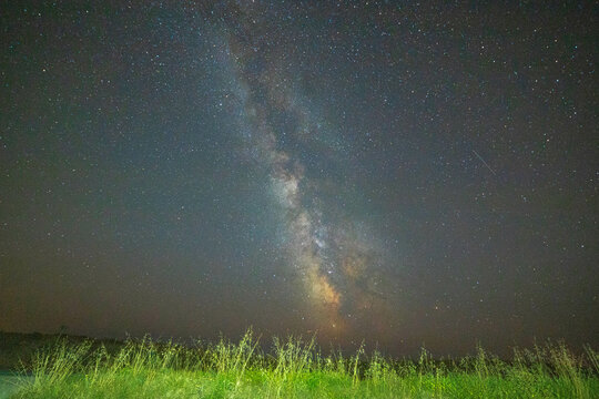 Night sky with the milky way core over green grass in country scenery. Brittany, France. Background with copy space.