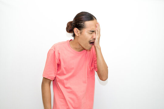 Asian, Indonesian man with long hair and bored face, sleepy and yawning standing wearing pink shirt. isolated on white background