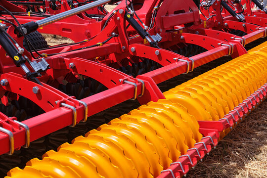 Close-up of a large modern plow yellow color or disc harrow for cultivating the land. New model of agricultural equipment.