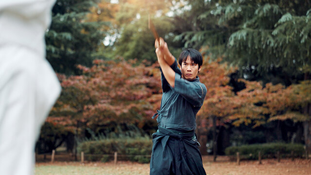 Sword, martial arts and man in park training fight, coaching and learning with outdoor samurai challenge. Weapon, warrior and Japanese people sparring together in nature for traditional bokken battle