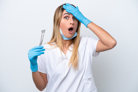 Dentist woman holding tools isolated on white background doing surprise gesture while looking to the side