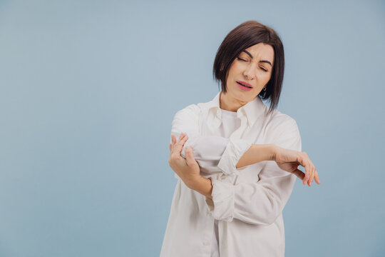 Brunette Woman Suffering From Elbow Pain on Blue Background