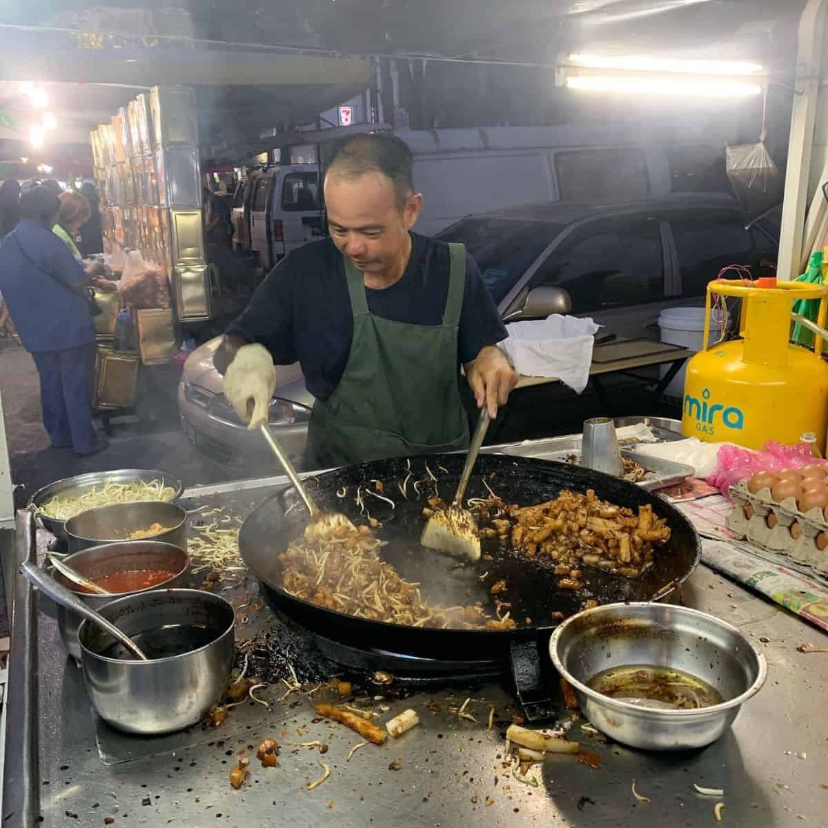 A local cook preparing a duck egg dish in Penang night market