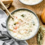 A bowl of homemade Clam Chowder with a spoon in it, topped with fresh cracked black pepper.