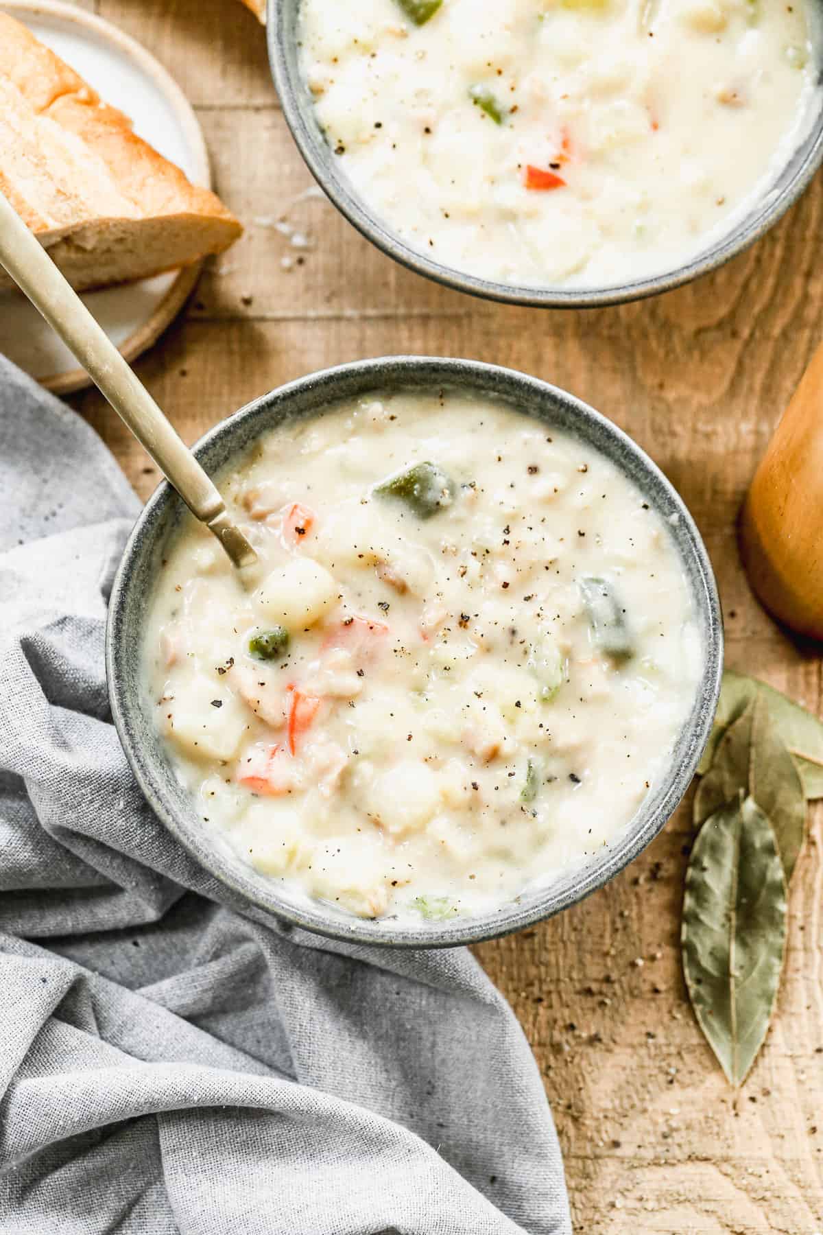 A bowl of homemade Clam Chowder with a spoon in it, topped with fresh cracked black pepper.