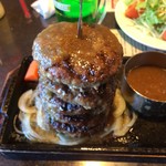 ハッピー バーグ - デカ盛り 「黒毛和牛タワーバーグ 1kg」ハンバーグ 1枚 1枚のサイズは、直径 15cm × 厚さ 3cm。それが 5枚、倒れないように「ステンレス製 平板式バーベキュー焼き串21cm」に串刺しにされて鉄板プレートに置かれている。