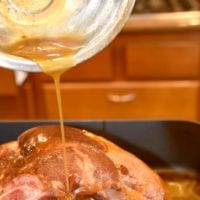 Drizzling a luscious baked ham glaze over a cooked ham in a cozy kitchen setting.