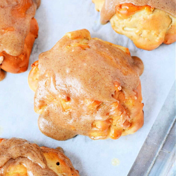 Air fryer apple fritters with a delectable cinnamon glaze rest perfectly on parchment paper.