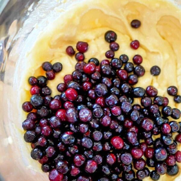 A bowl of muffin batter with fresh huckleberries on top, ready to be mixed, makes for an easy muffin recipe that's sure to delight.