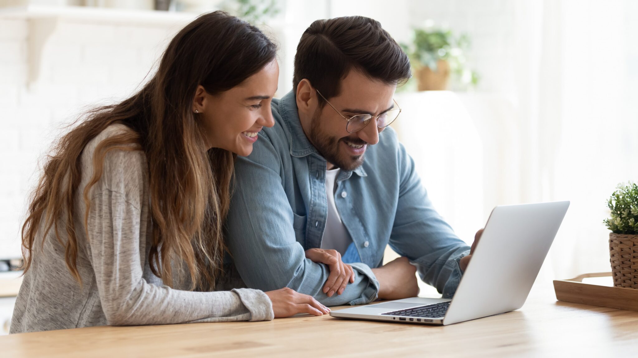 A smiling couple exploring online car buying options on a laptop, enjoying a convenient and stress-free experience at home