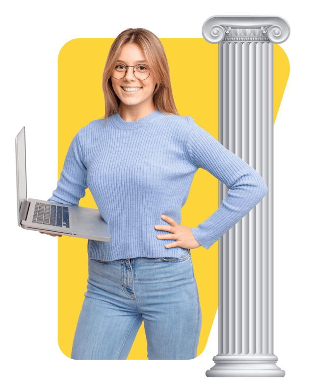 A woman stands in front of a column, holding a laptop and appearing focused on her work.