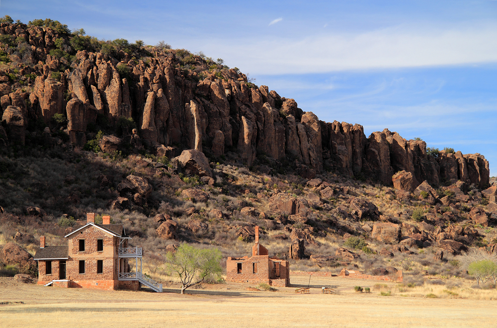 Abandoned brick buildings with rocky mountains in the background on a sunny day