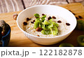 cooked oatmeal with kiwi, honey and nuts in a bowl on a wooden table 122182878