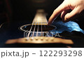 Finger Playing Guitar Strings on a Black Guitar 122293298