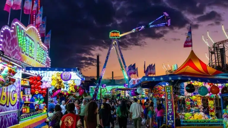 A fair illuminated at night with multiple rides going