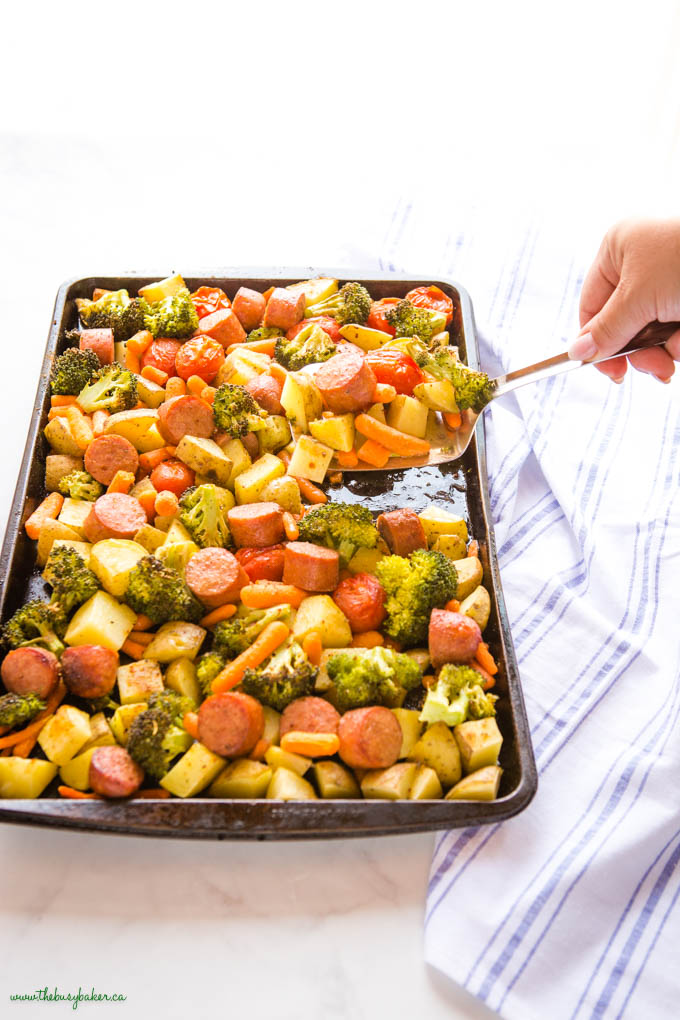 hand holding a lifter serving sausage sheet pan dinner