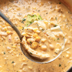 A generous ladle of white chicken chili with shredded chicken, beans, corn and chopped cilantro.