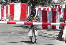 A Taliban fighter stands guard at the entrance of the police headquarters in Ghazni on August 12, 2021