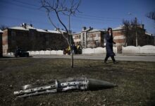 A woman looks at the remains of a missile in Ukraine's Kharkiv