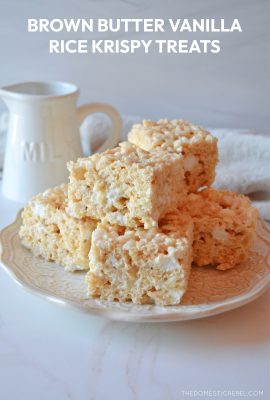 a little stack of brown butter vanilla rice krispy squares sits on a white lacy plate against a white background.