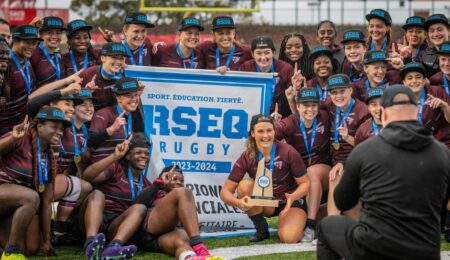 womens rugby team stands in front of banner